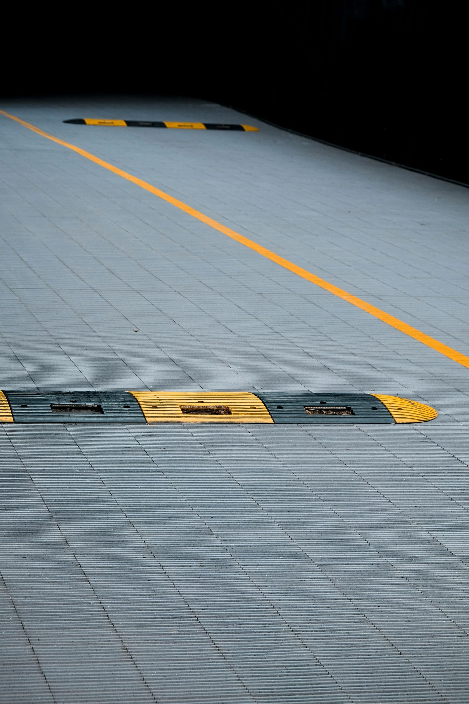 A yellow and black speed bump on the side of a road