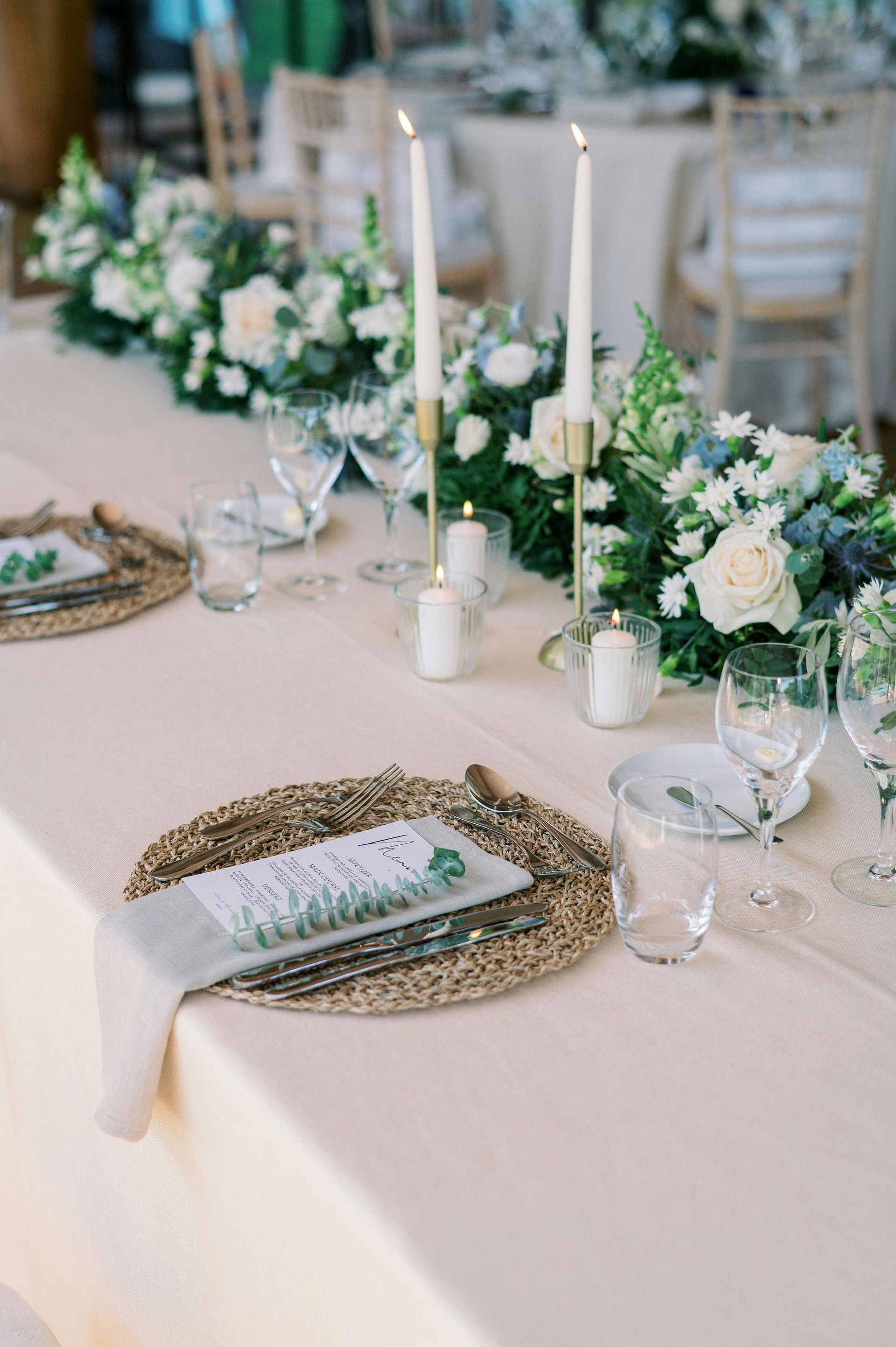 A long table with plates , candles , and flowers on it.