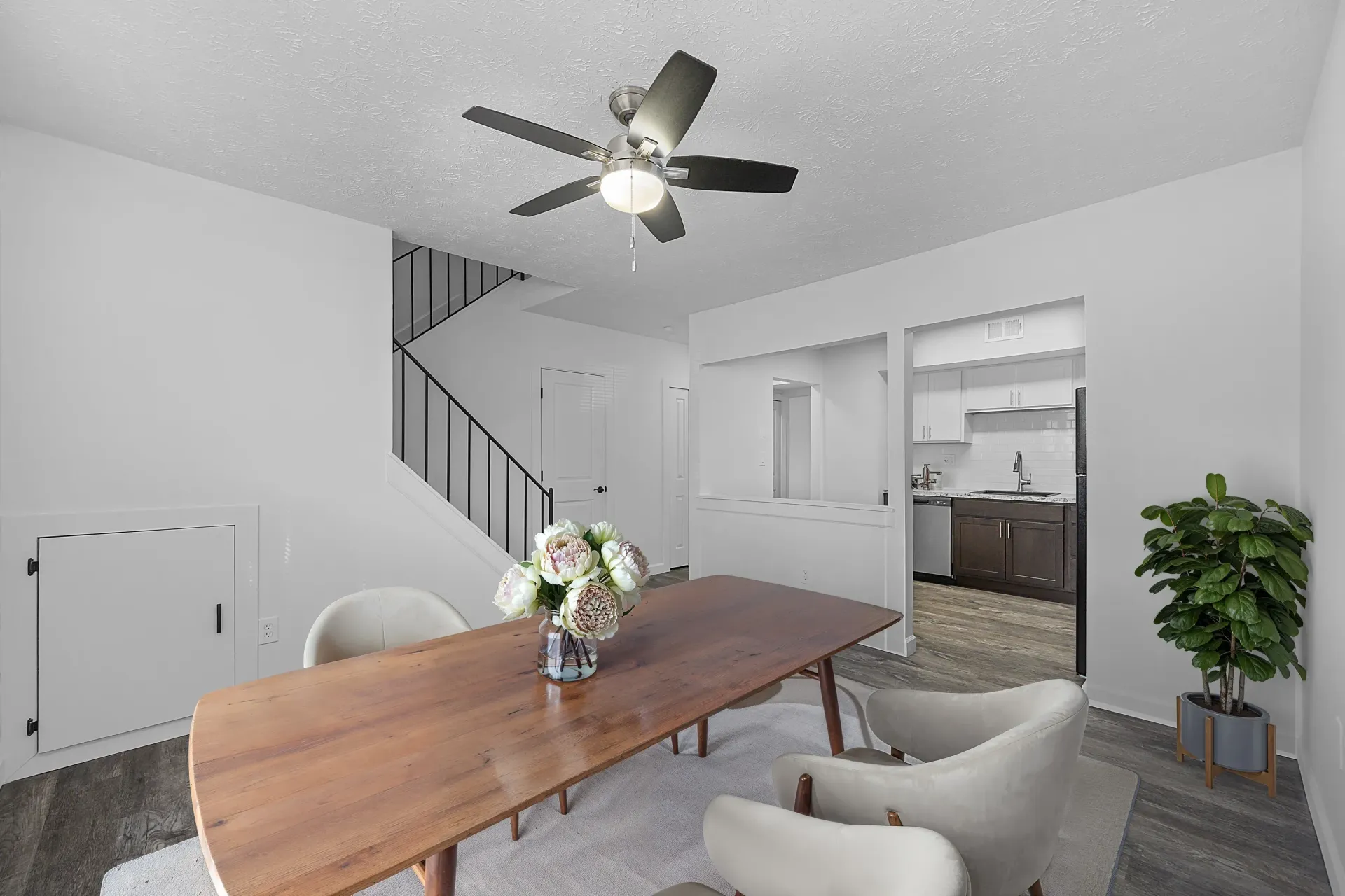 Open-concept living and dining area with stairs and kitchen pass-through in a modern apartment.