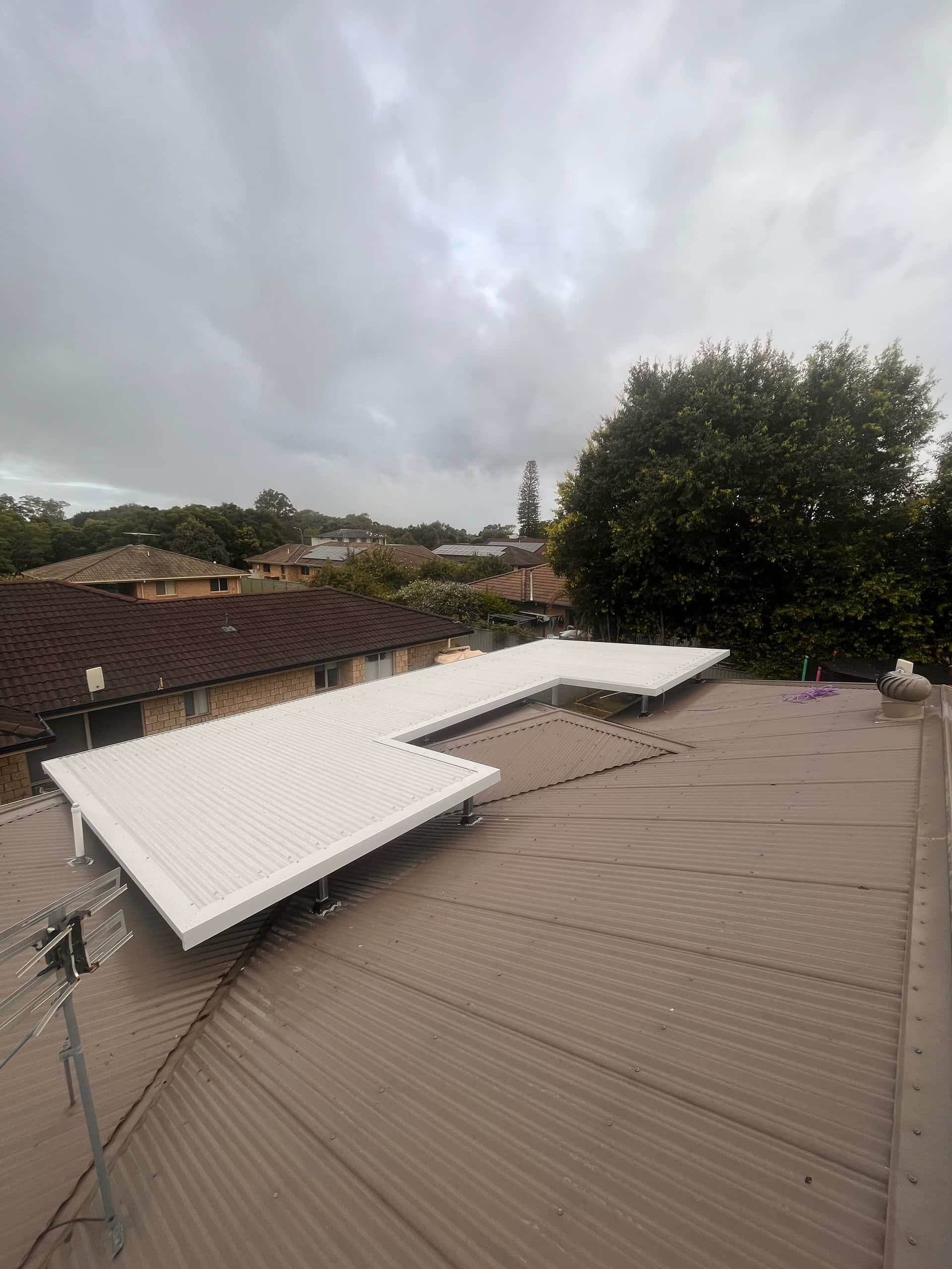 A White House With a Gray Roof and a Yellow Flower in the Foreground — Eli Mcauley Constructions in Yamba, NSW