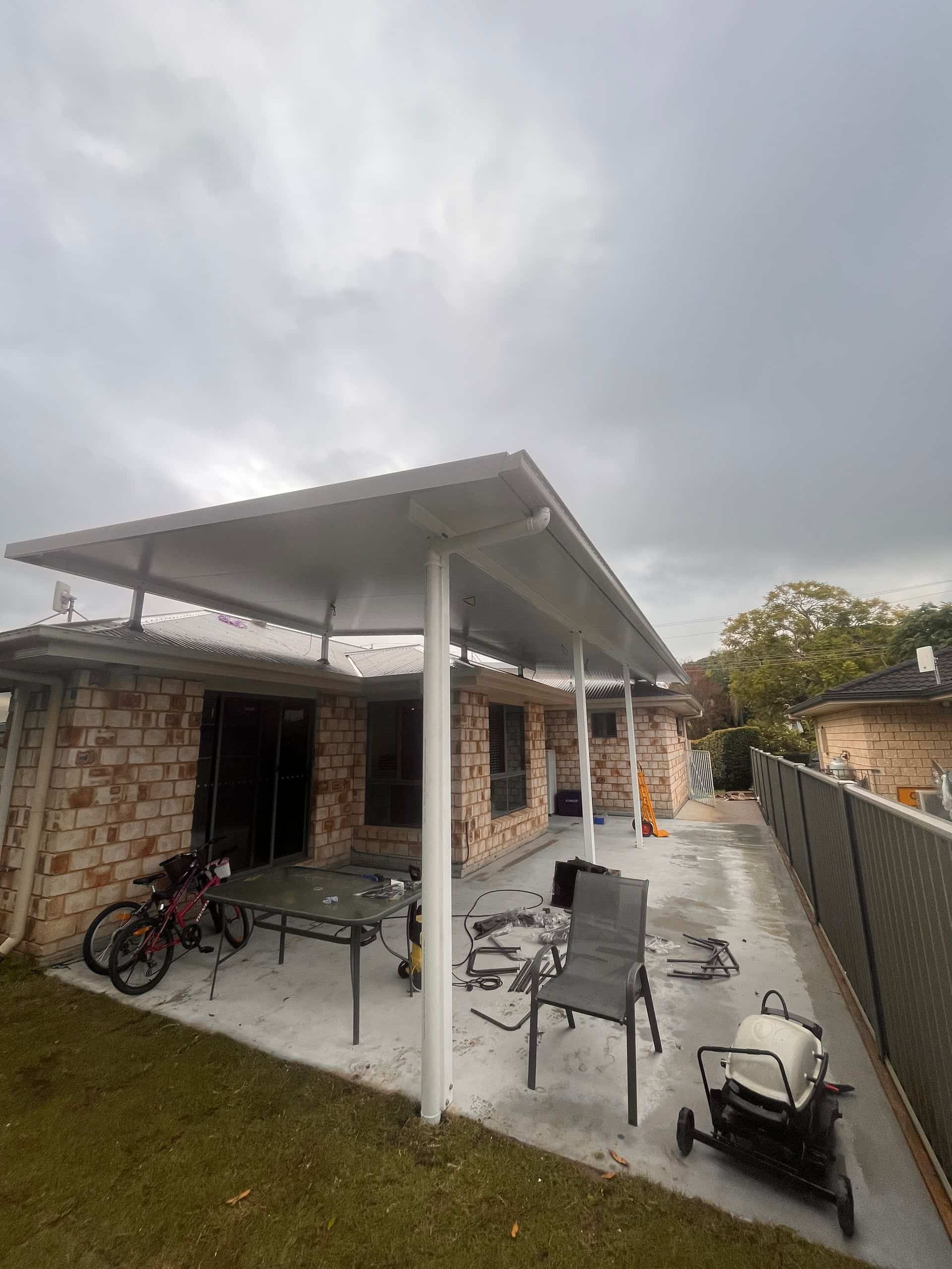 White-roofed patio with support columns adjoins a brick house — Eli Mcauley Constructions in Grafton, NSW