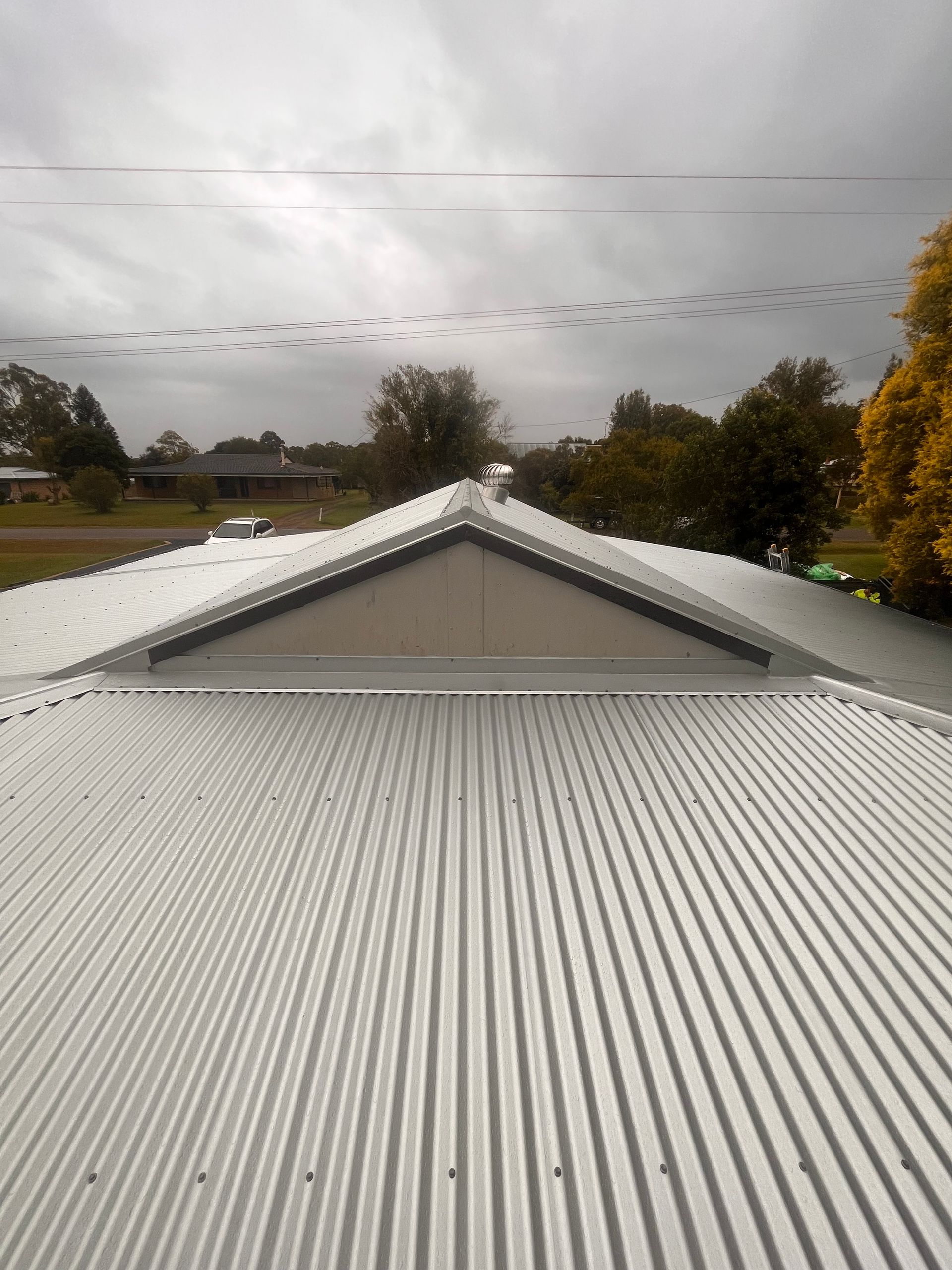 Corrugated metal roof with a triangular skylight, overcast sky, rural setting — Eli Mcauley Constructions in Grafton, NSW