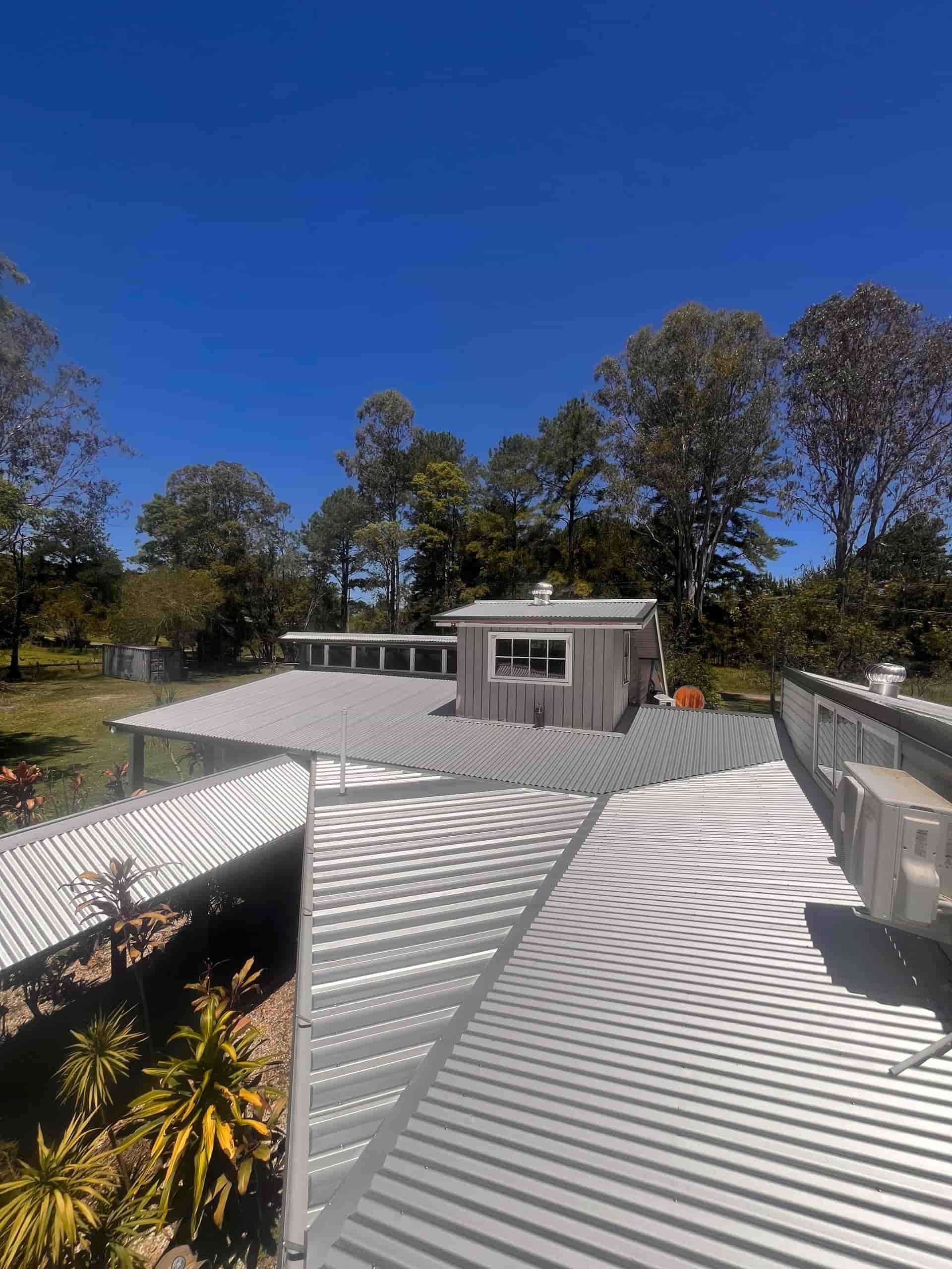 Metal roof with air conditioning unit, trees and clear blue sky— Eli Mcauley Constructions in Grafton, NSW