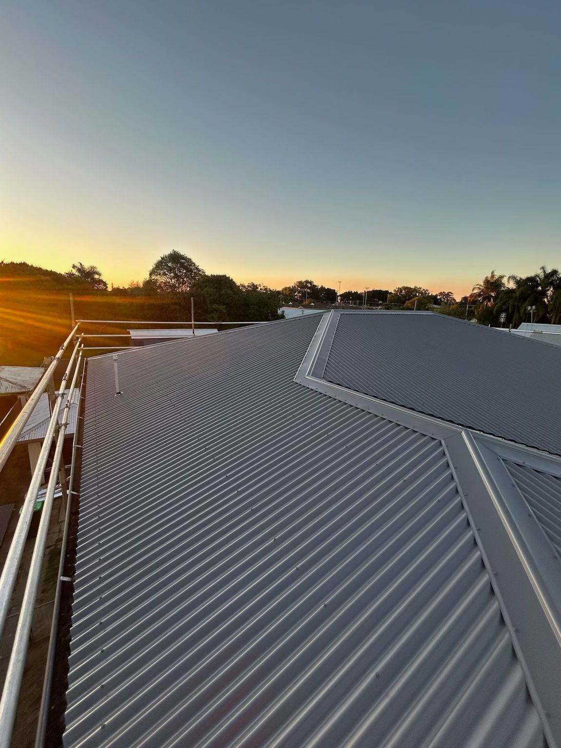 Metal roof with railings, against a sunset sky — Eli Mcauley Constructions in Yamba, NSW