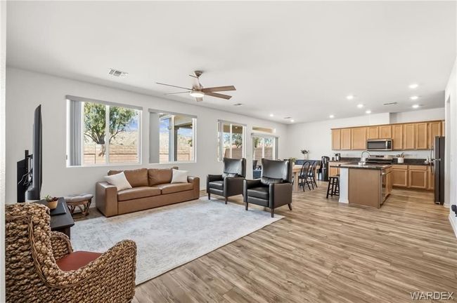 Bright open-concept living room and kitchen with LVP floors, white walls, and large windows