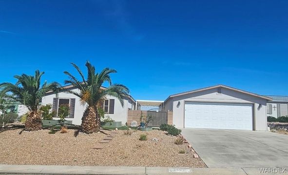 Single-story desert home with 50-foot garage, palm trees, and gravel yard under a clear blue sky