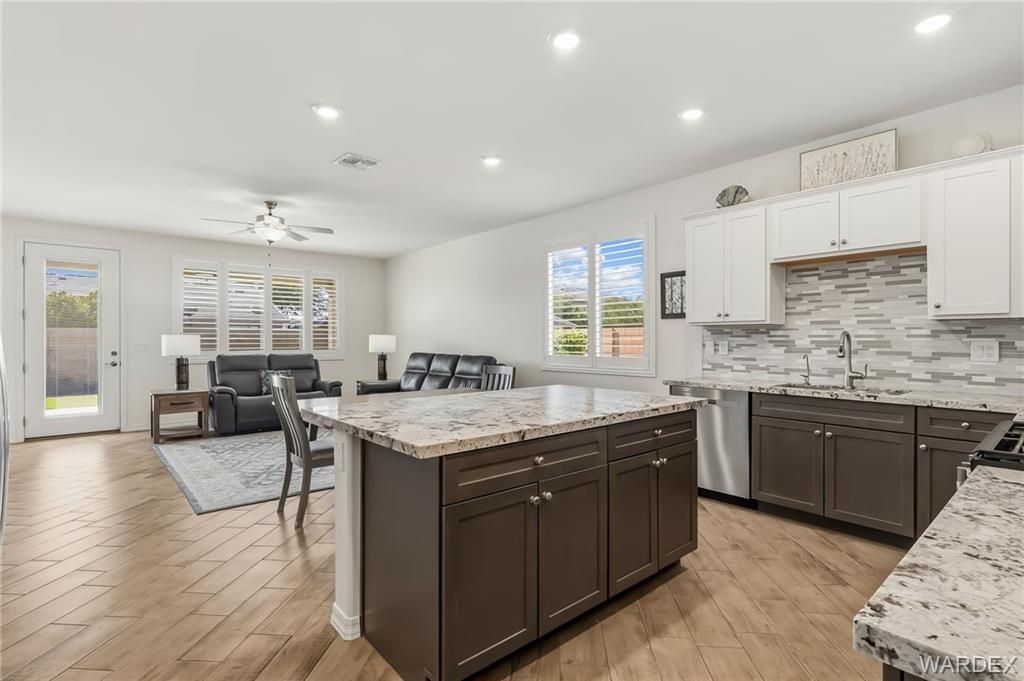 Bright open kitchen and dining area with island, dark cabinets, white countertops, and tiled backsplash