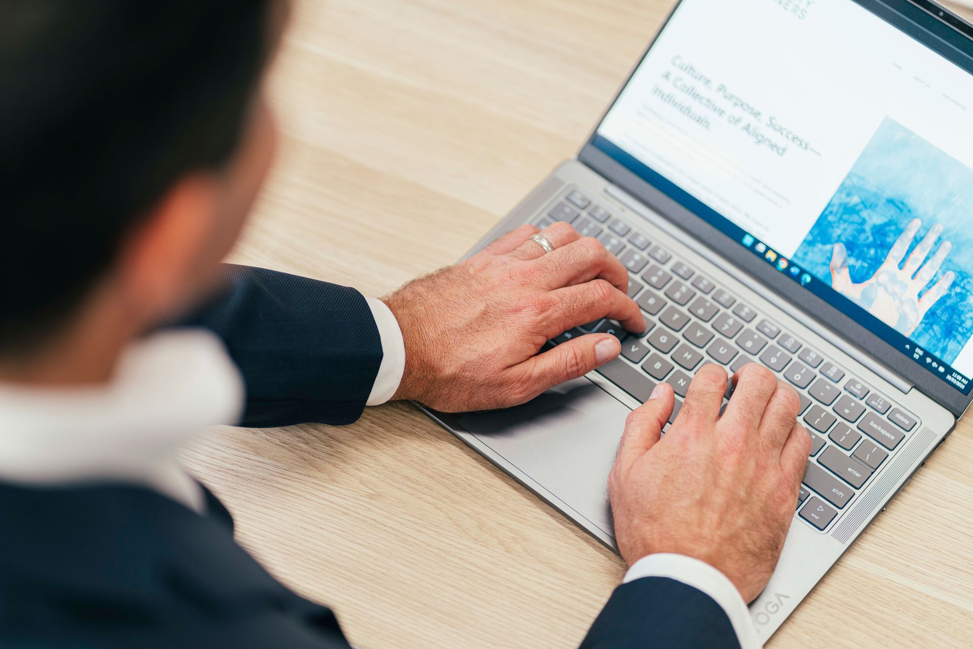 Person typing on a laptop at a desk with a blue graph on the screen
