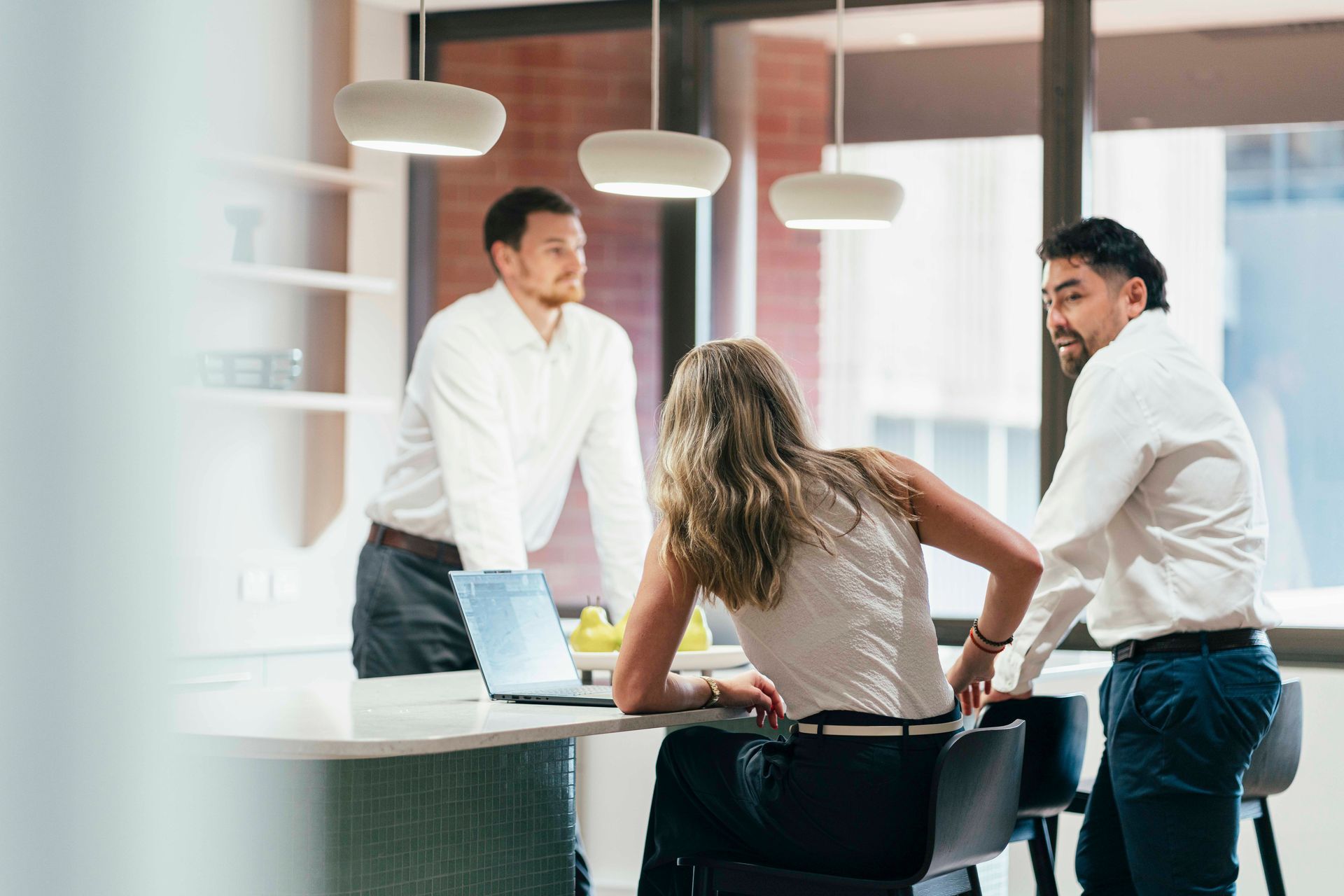 Three colleagues in a modern office, smiling and shaking hands during a meeting