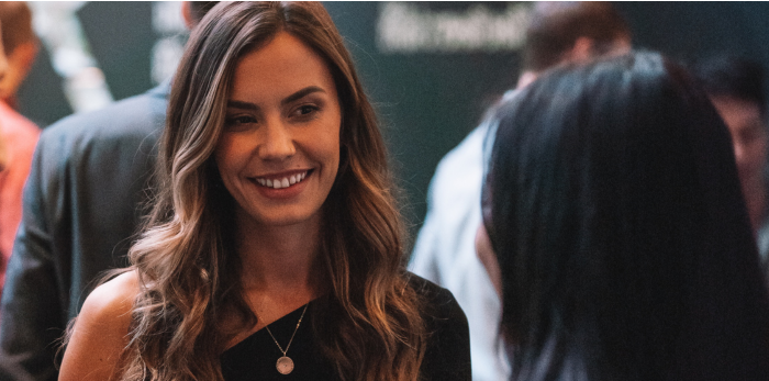 Woman speaking with another person in a workplace setting, with an unfocused background creating a professional atmosphere