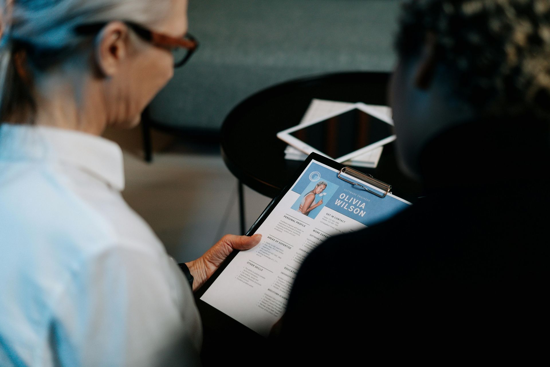 Two people reviewing a document in a meeting room, one holding a brochure or report.
