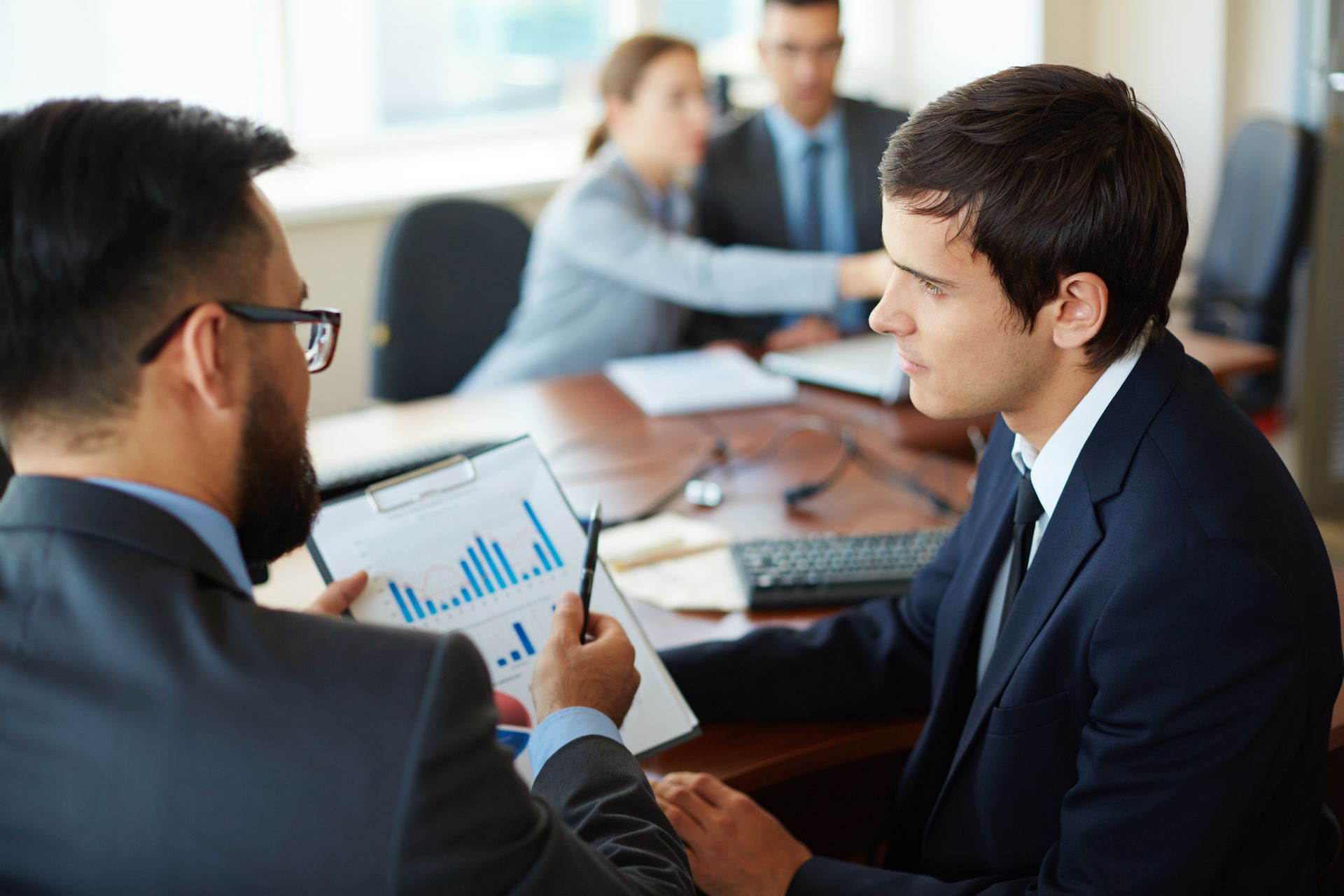 Business meeting with two people discussing a chart in a conference room