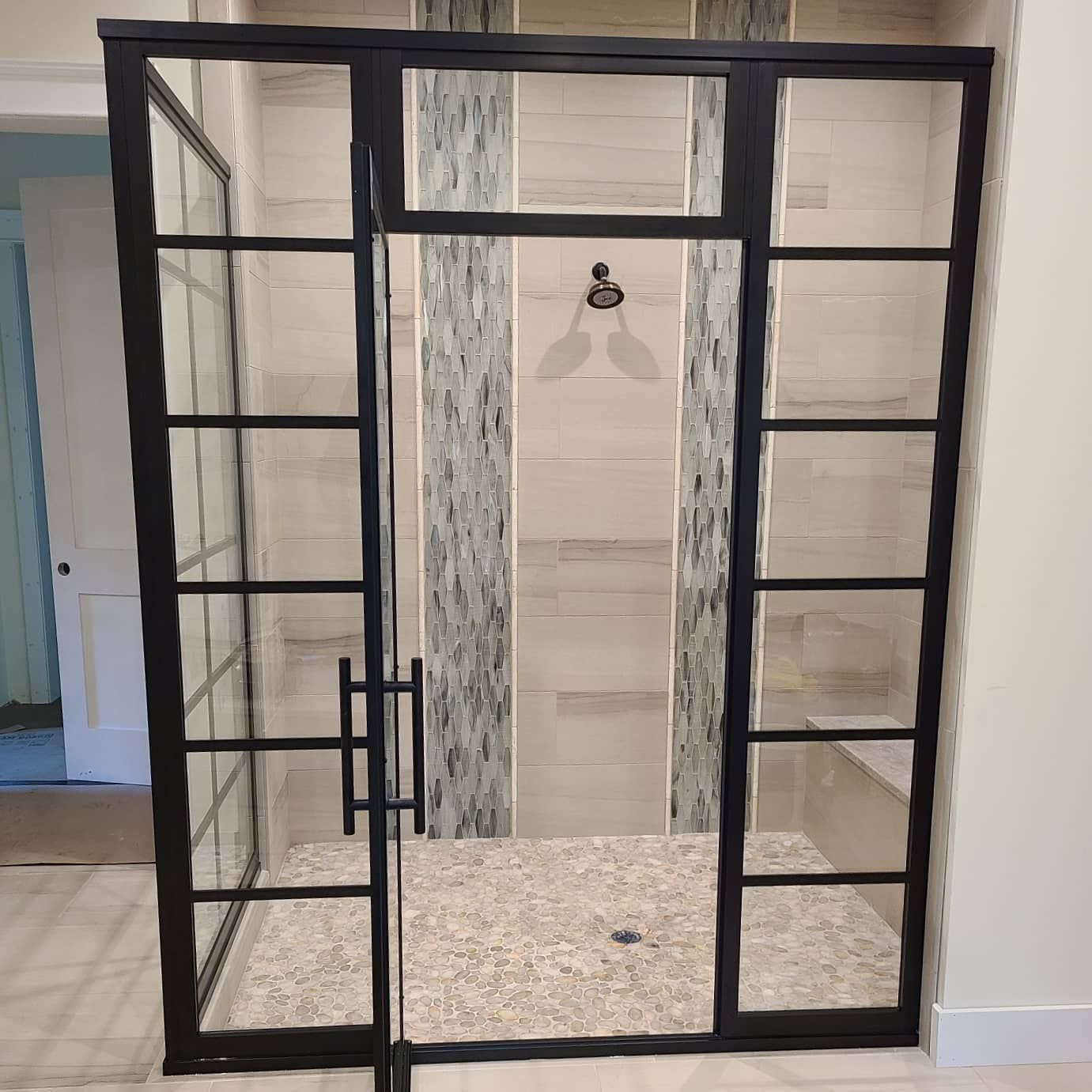 A walk in shower with a black frame and glass doors