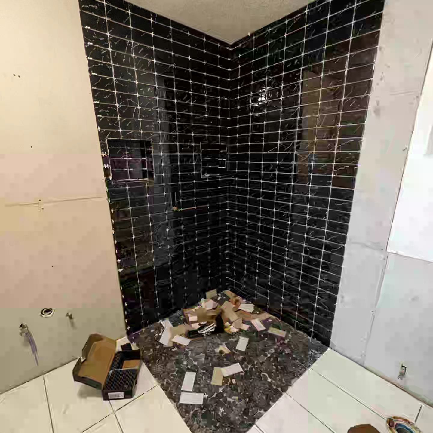 A bathroom under construction with black tiles and boxes on the floor.