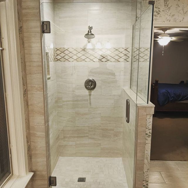 A bathroom with a walk in shower with a glass door.