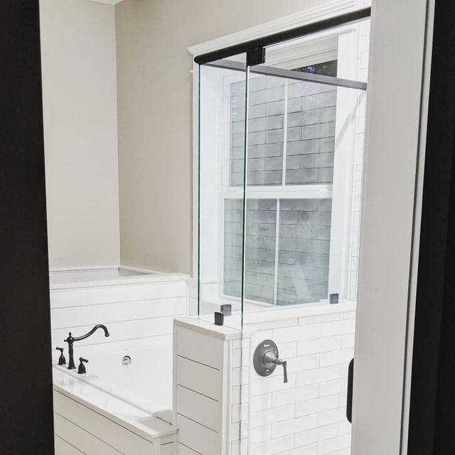 A bathroom with a tub , shower and window.