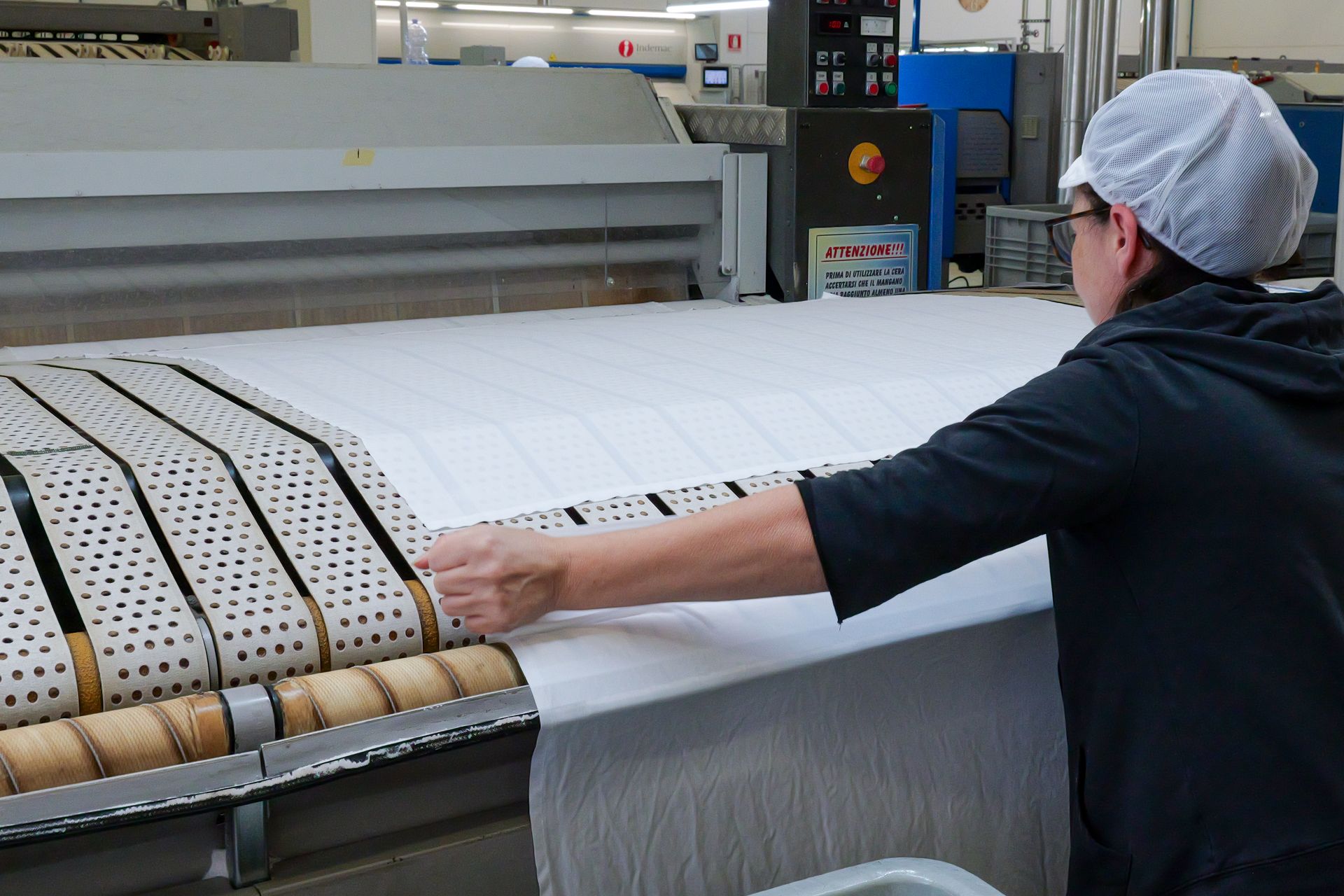 Operaio addetto alla gestione di una grande macchina industriale per la lavorazione di tessuti.