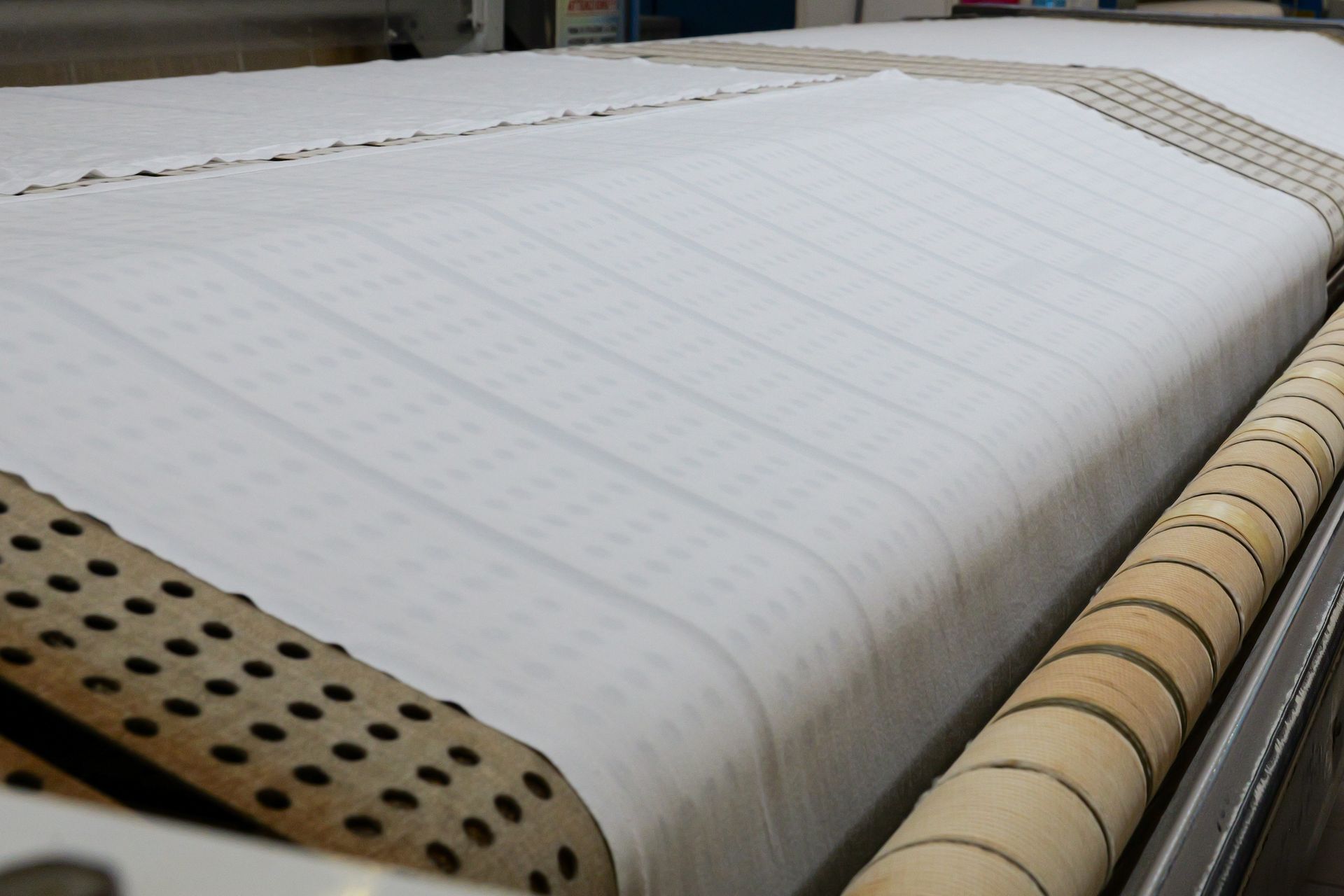 Rotolo di carta bianca su macchina industriale con rulli perforati color beige