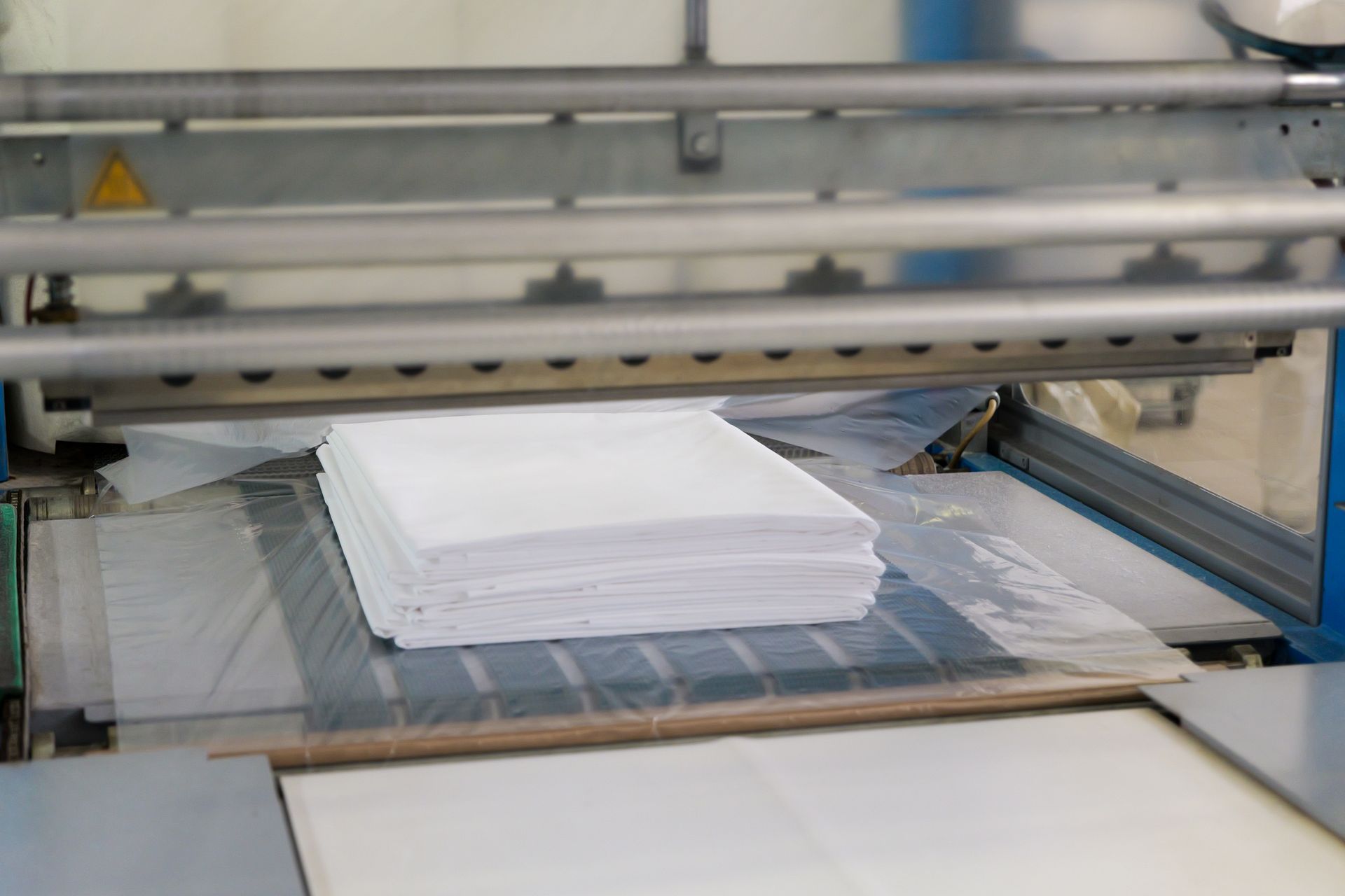 Pila di fogli di carta bianca su un nastro trasportatore industriale in una macchina da stampa o da taglio