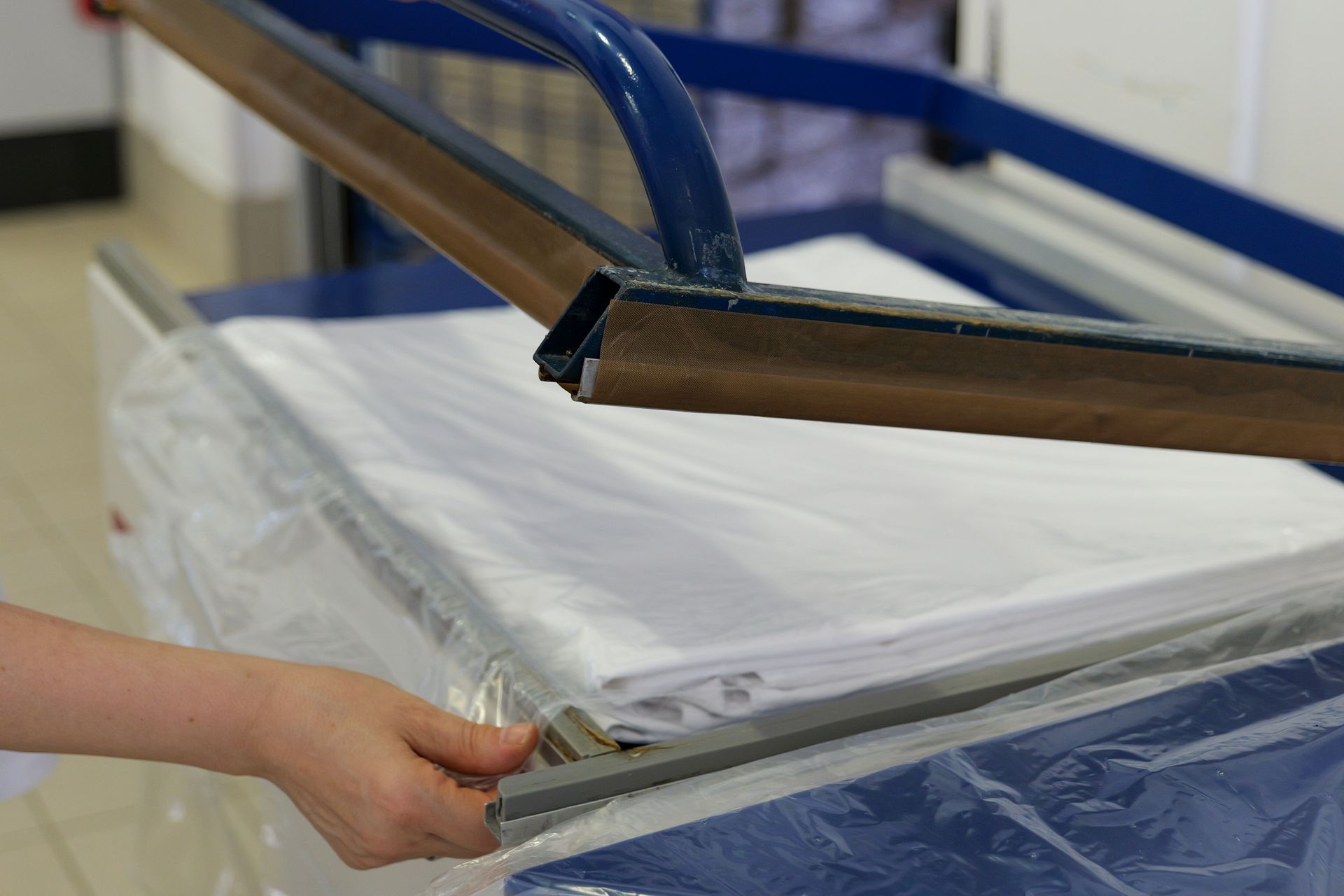 Una persona trascina un telaio per serigrafia blu su un telo di tessuto bianco