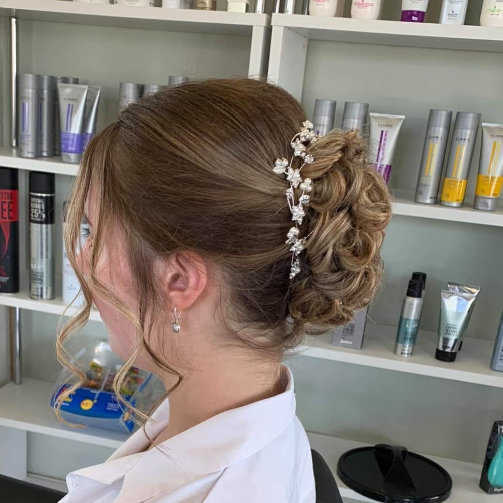 A Woman With Her Hair in a Bun is Standing in Front of a Shelf Full of Hair Products — Lush Hair Studio in Tumbi Umbi, NSW