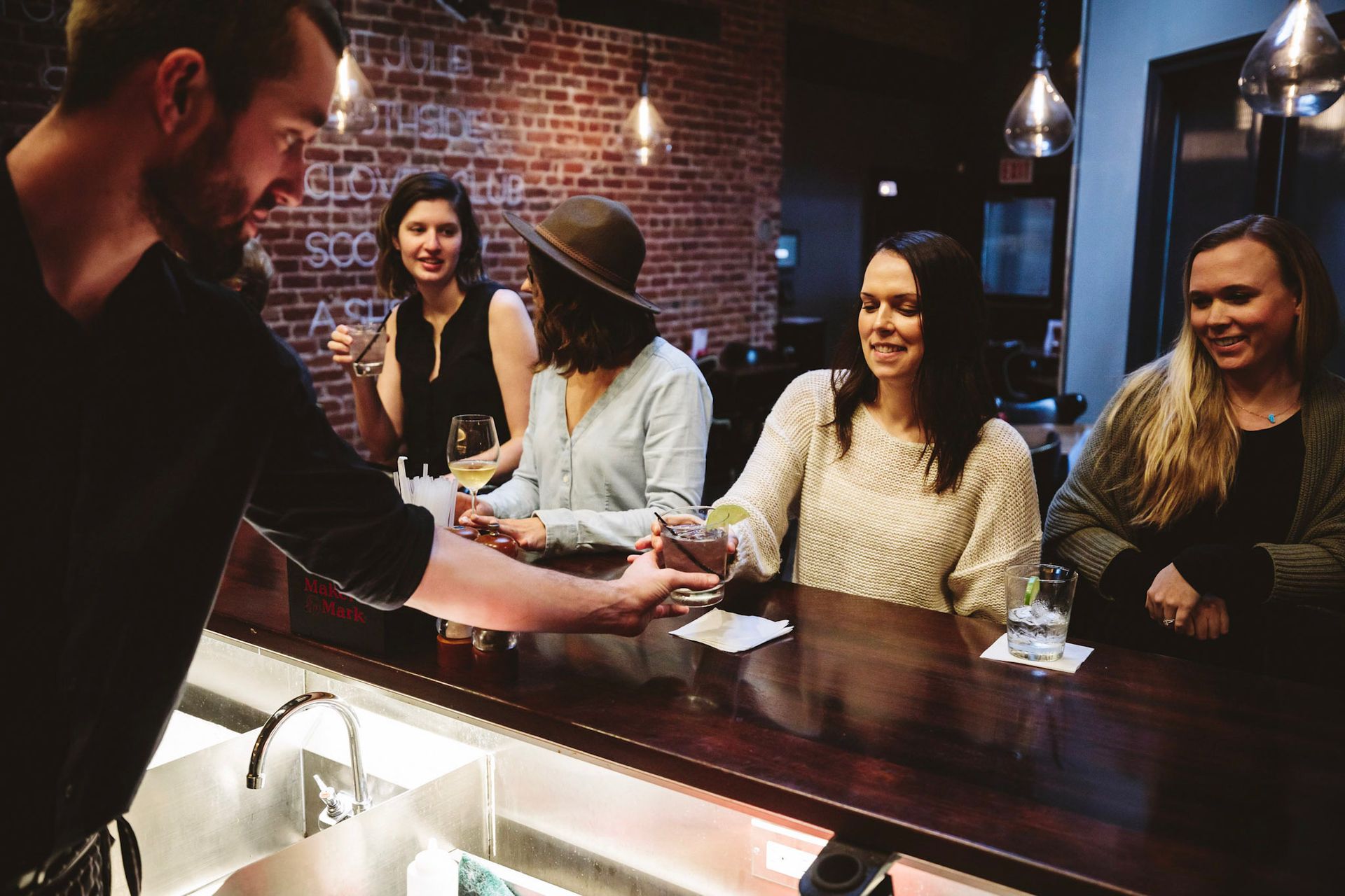 A group of people are sitting at a bar talking to a bartender.