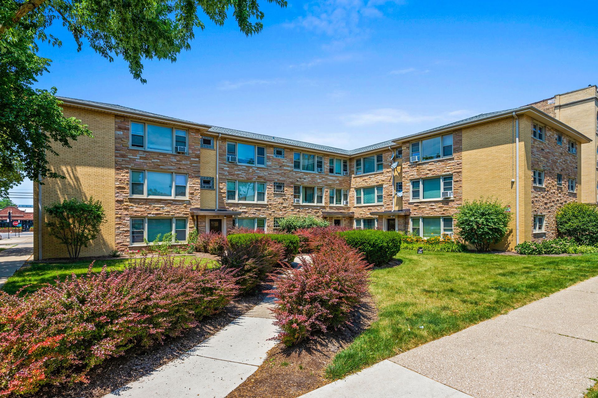 A large apartment building with a lot of windows and a sidewalk in front of it.