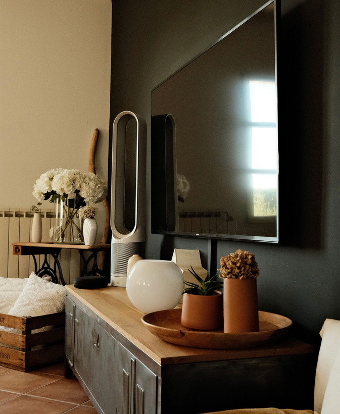 Modern living room with a TV, wooden console, lamp, vase, and decorative accents
