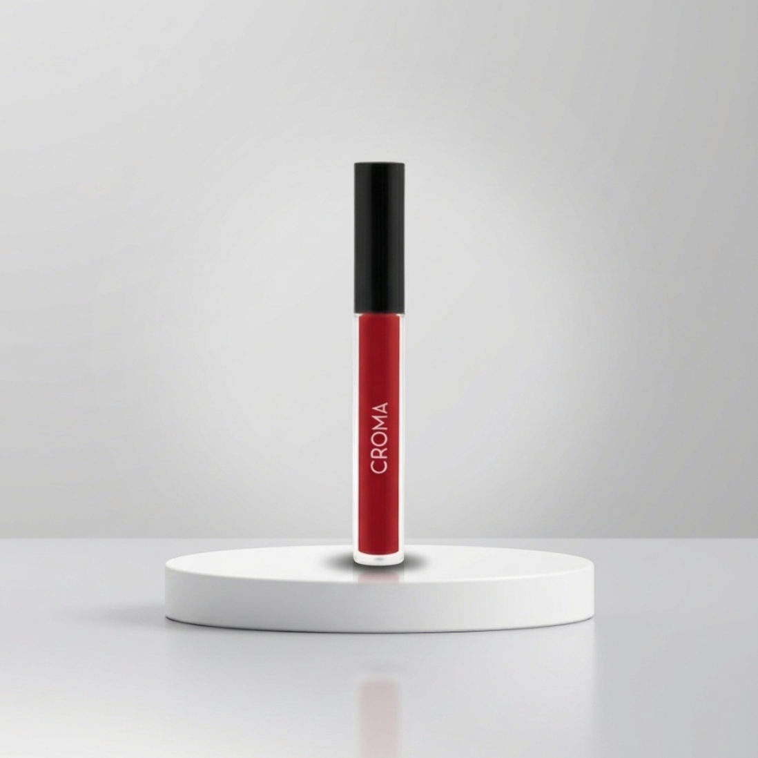 Tubo de brillo labial rojo con tapa negra sobre un pedestal blanco sobre un fondo gris.