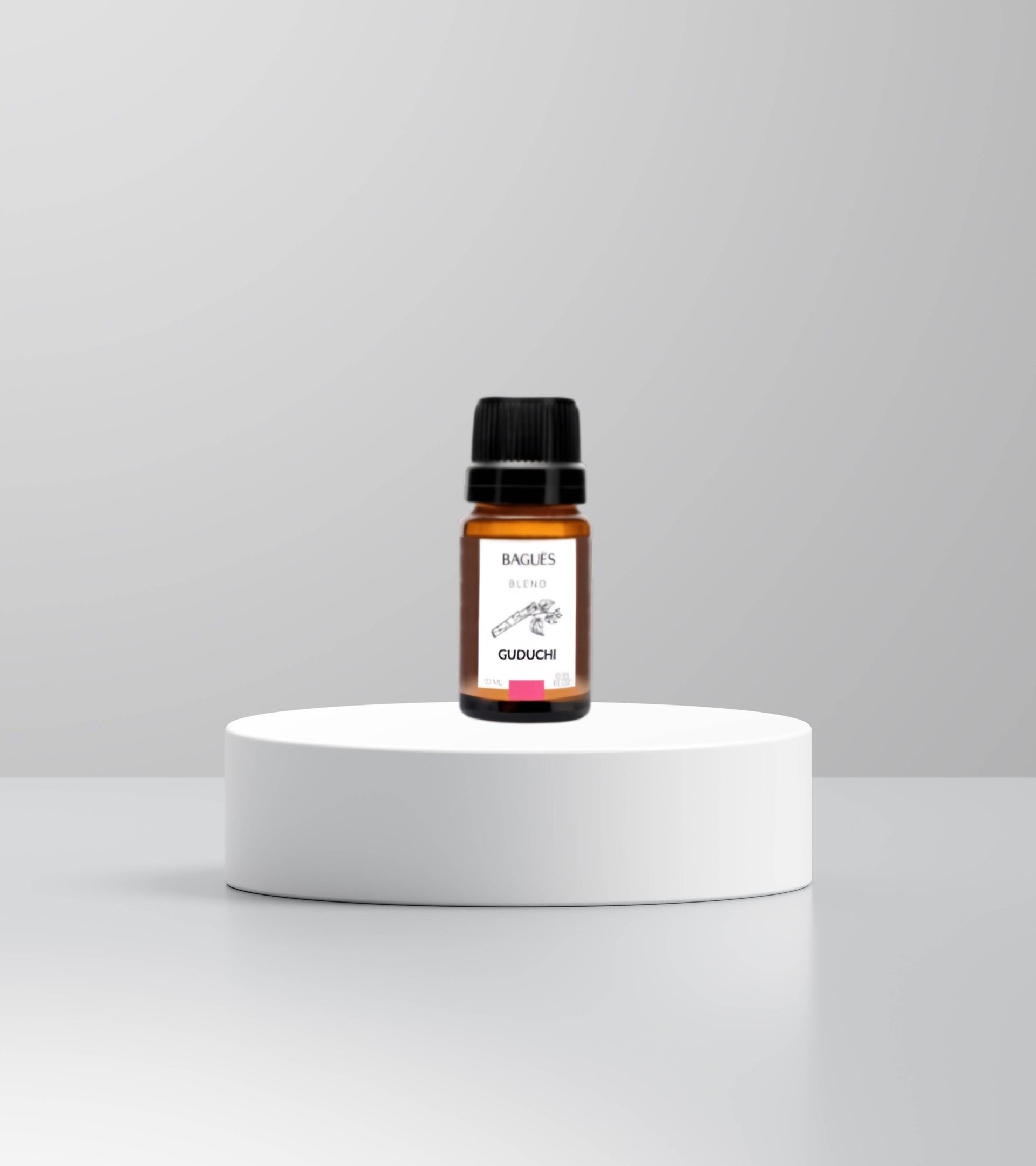 Frasco pequeño de color ámbar para aceites esenciales con tapa negra sobre un pedestal blanco sobre un fondo gris.