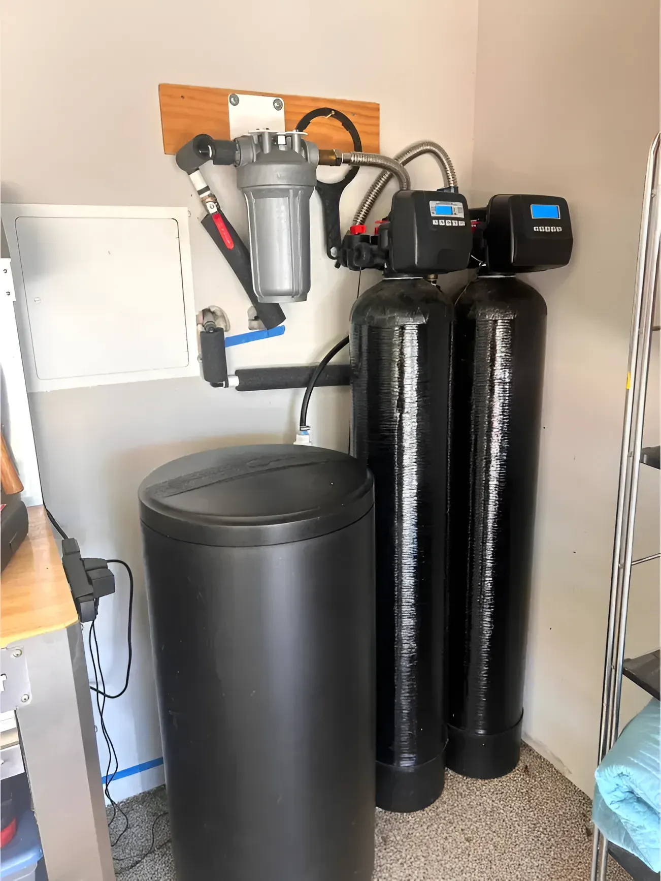 Water filtration system in a garage setting; includes tanks, a filter, and a salt container.