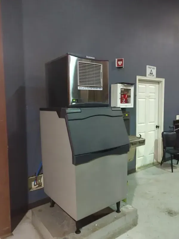 Ice machine in room with dark blue walls, a door, and a fire alarm.