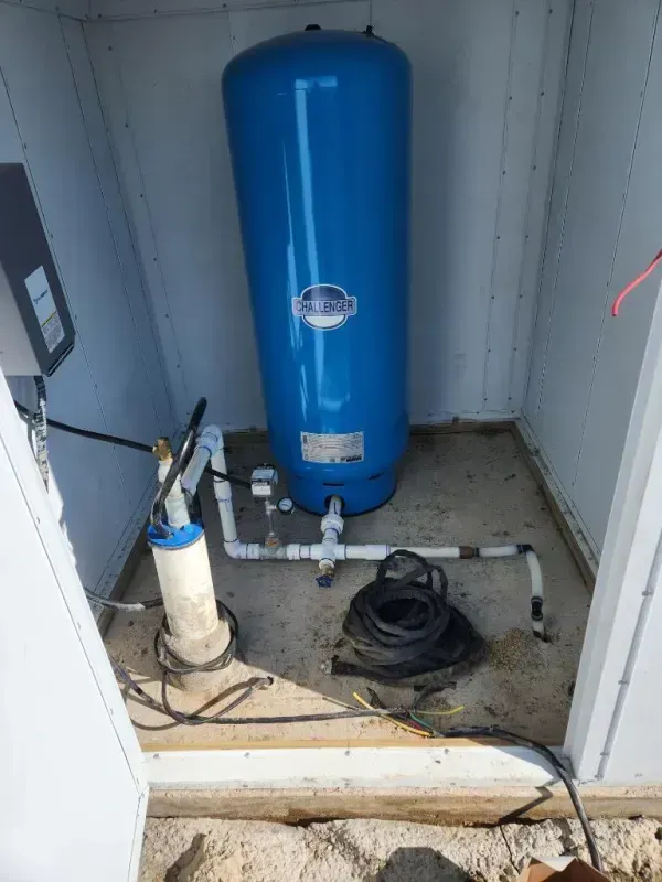 Blue water pressure tank and well components in a white enclosure.