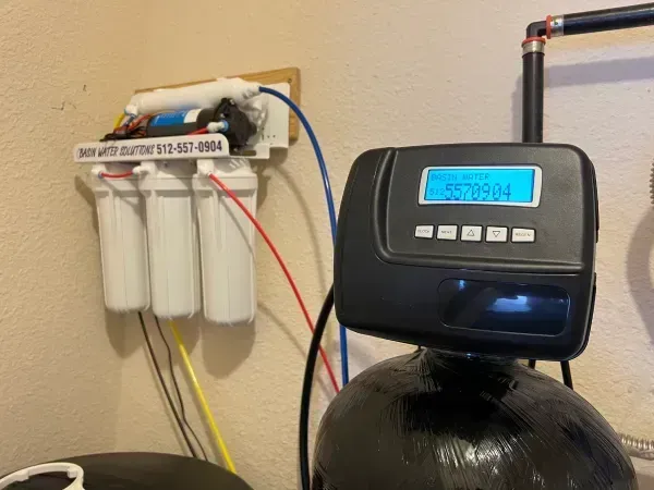 Water filtration system with three filters and a digital control panel on a black tank.