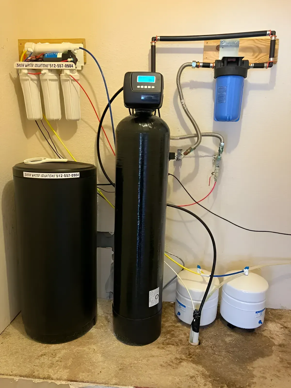 Water filtration system with tanks, filters, and control panel against a beige wall.