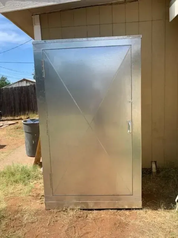 Metal storage cabinet with a door in a backyard.