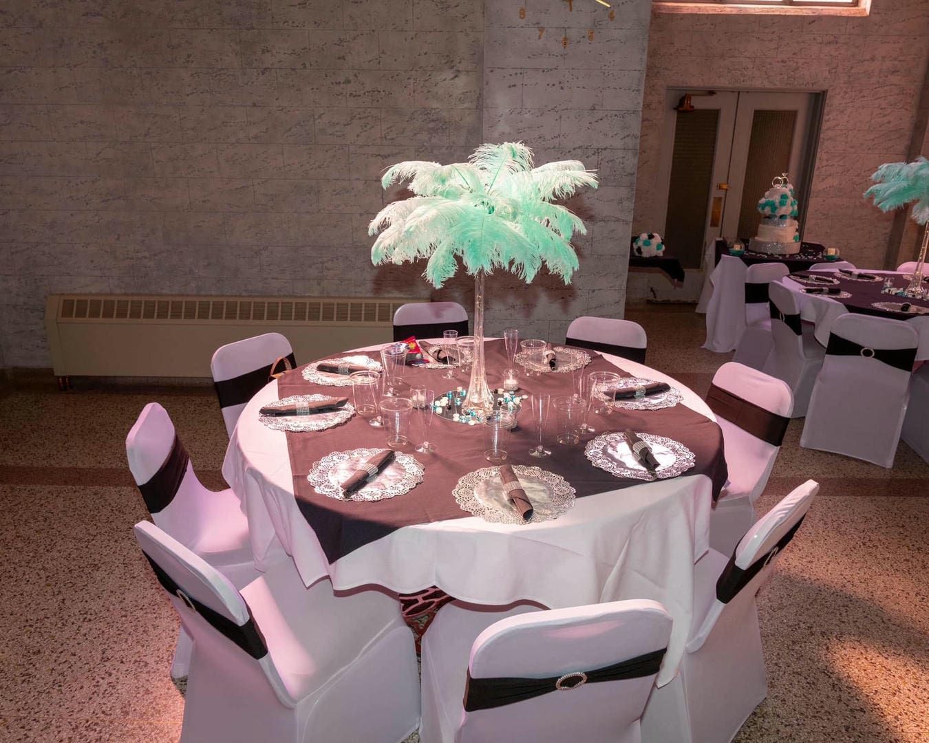 A table set for a wedding reception with feather centerpieces