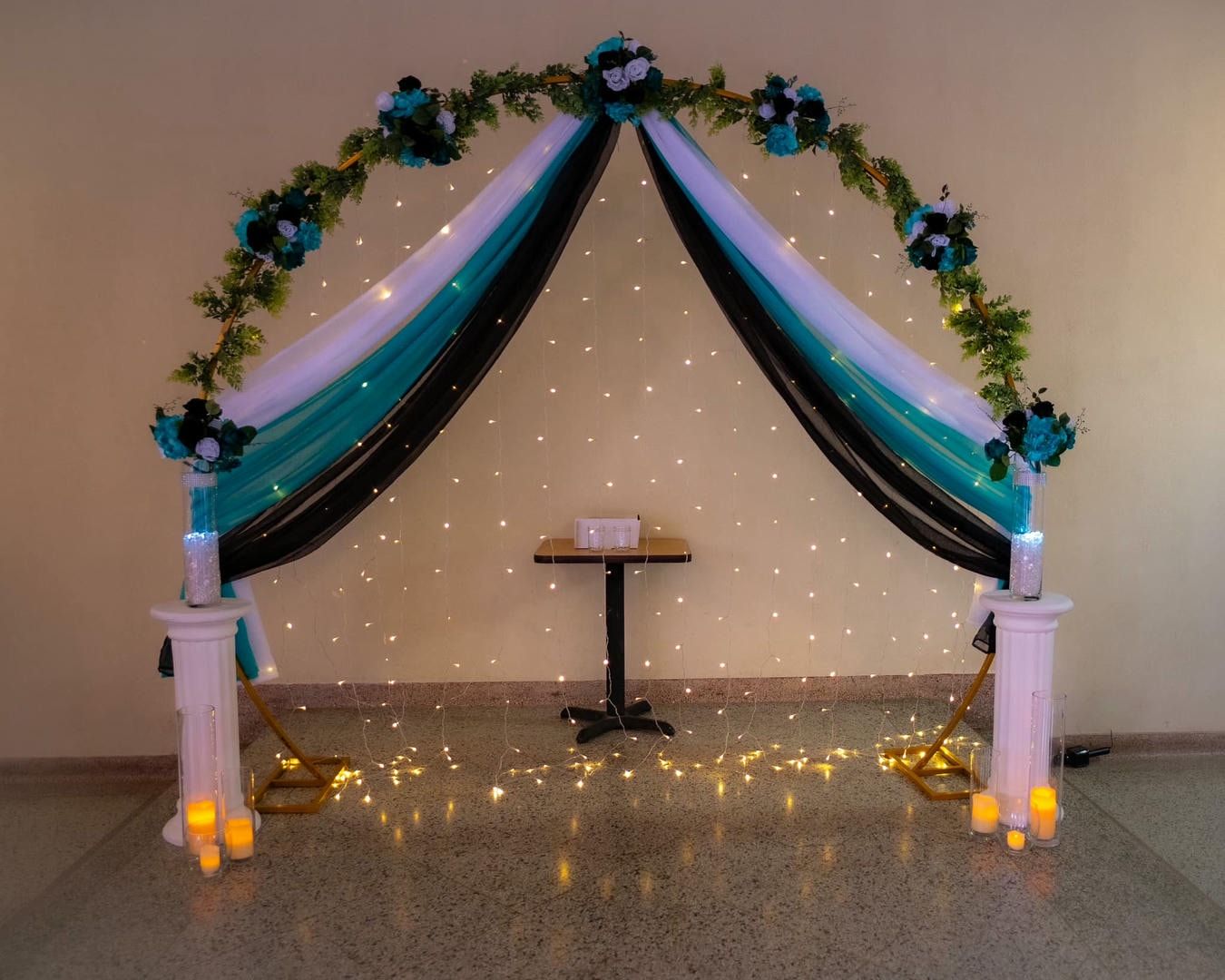 A black and white arch with flowers and lights