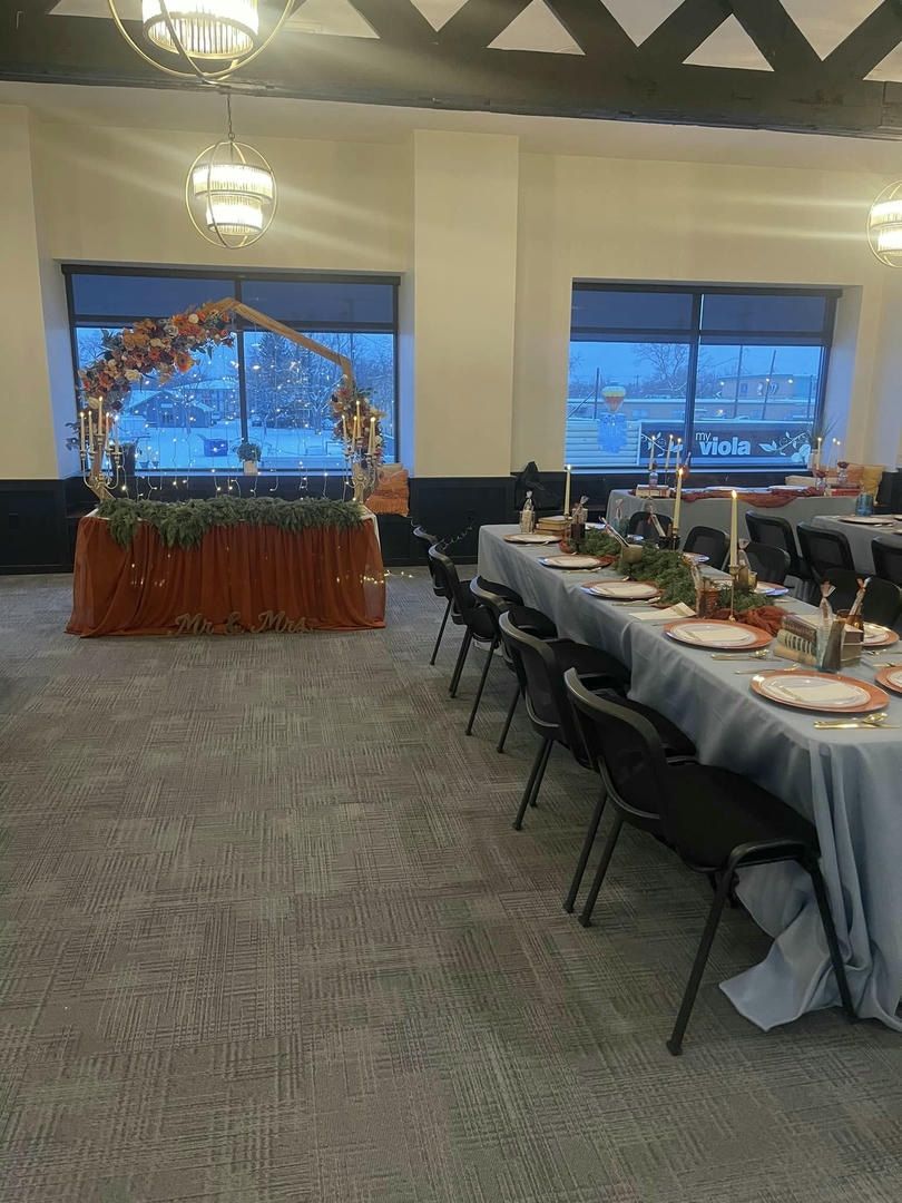 A room with tables and chairs set up for a wedding reception.