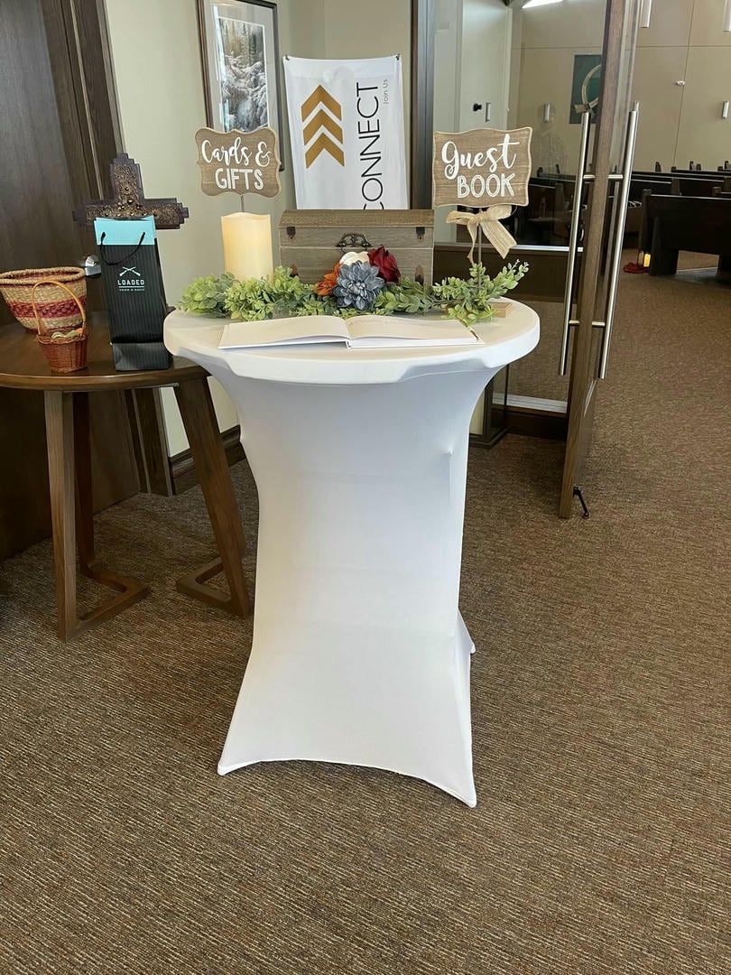 A white table with a guest book sign on it in a room.