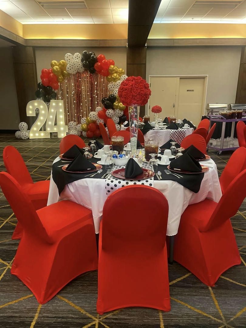 A room decorated for a birthday party with red chairs and tables.