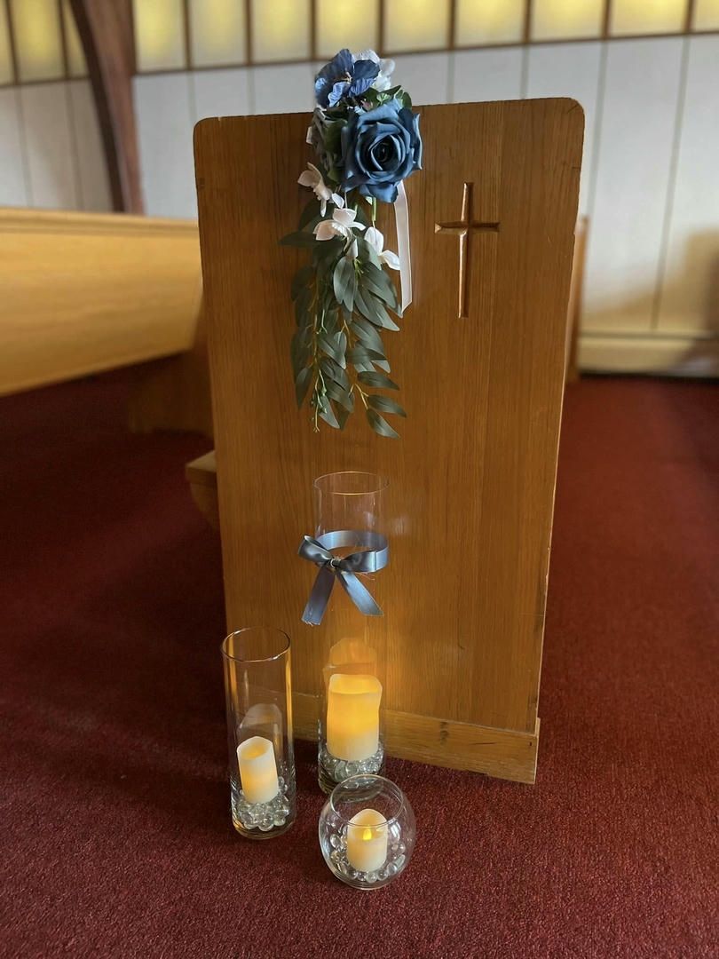 A wooden podium with candles and flowers on it in a church.