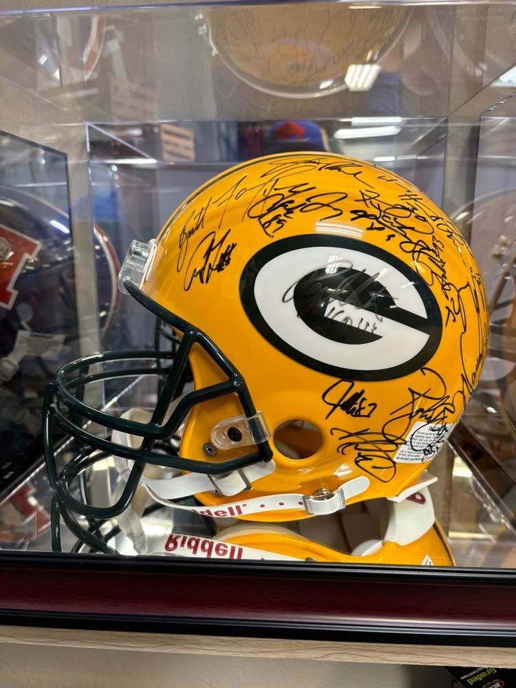 A green bay packers football helmet is in a glass case.