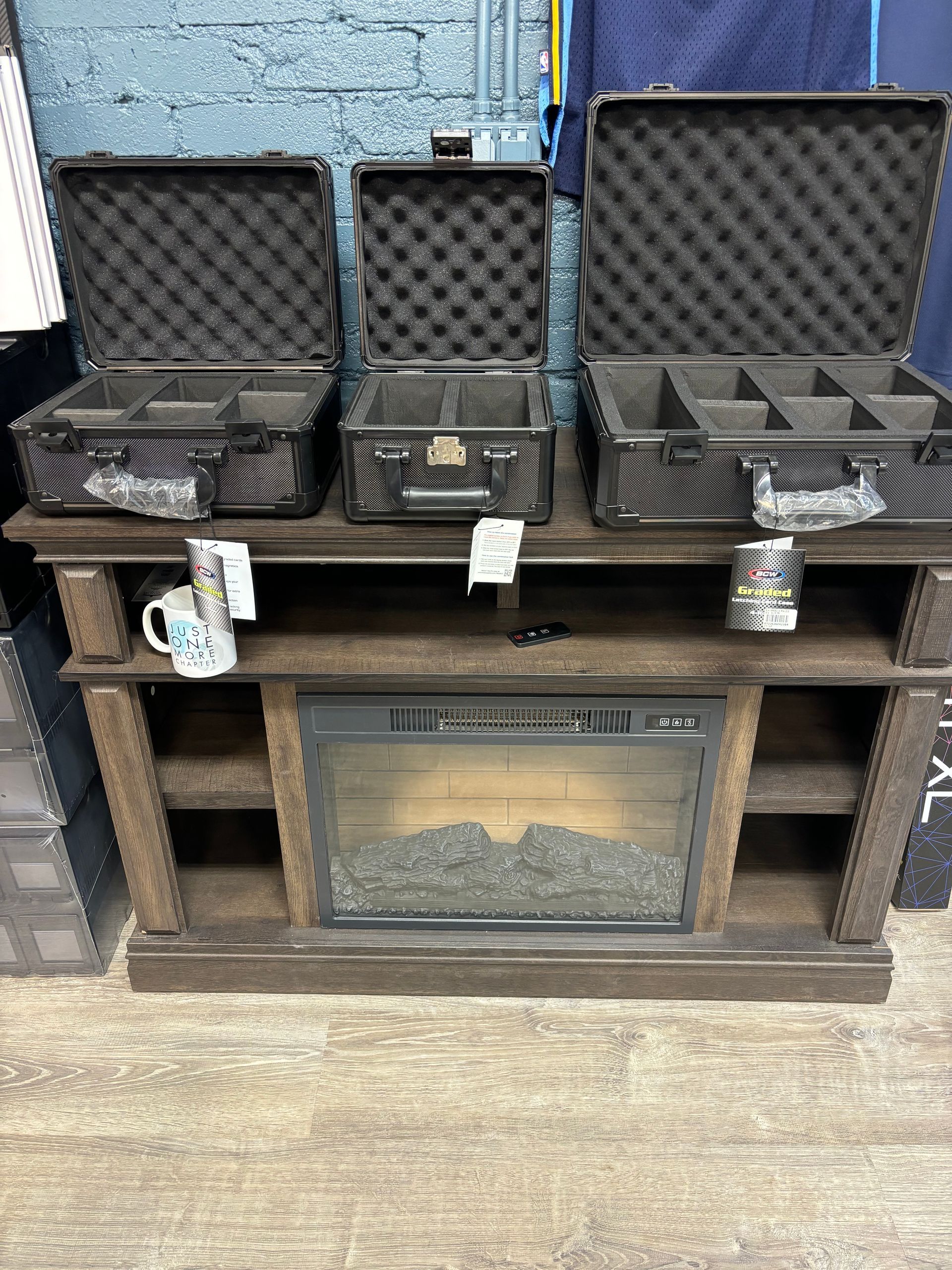 A wooden entertainment center with a fireplace and cases on top of it.