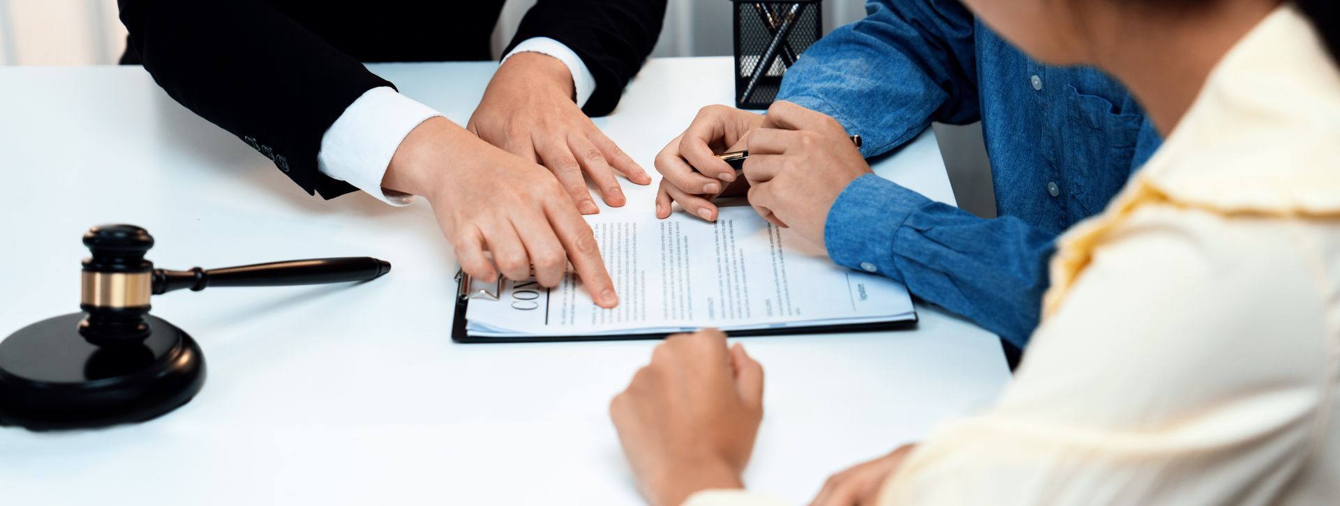 A divorce attorney guides clients with a gavel symbolizing justice in paperwork review.