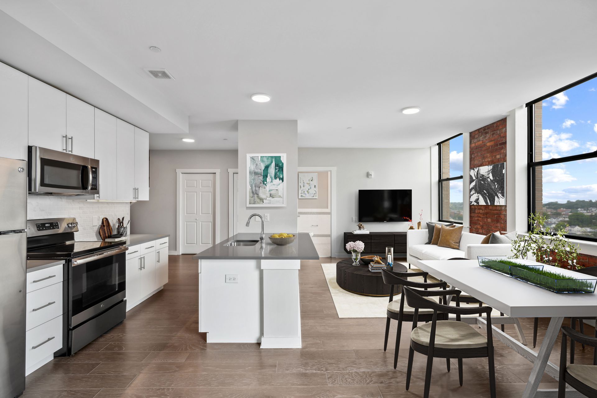 A kitchen with white cabinets and stainless steel appliances and a dining table and chairs.