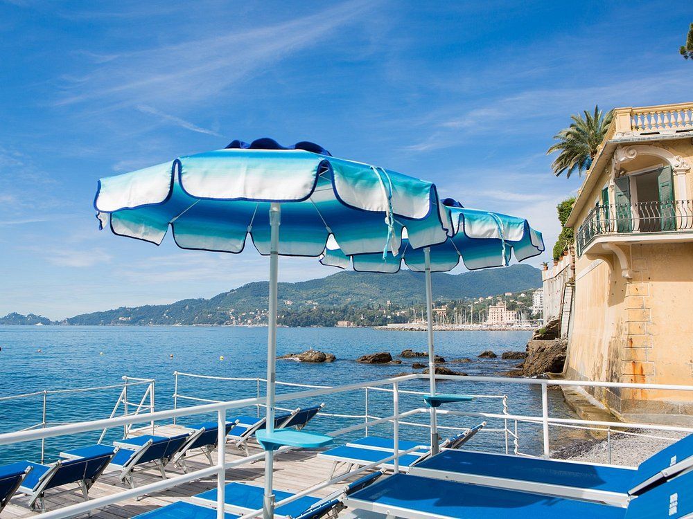 Ombrelloni blu sopra sedie a sdraio in un patio sul mare con vista sull'oceano.