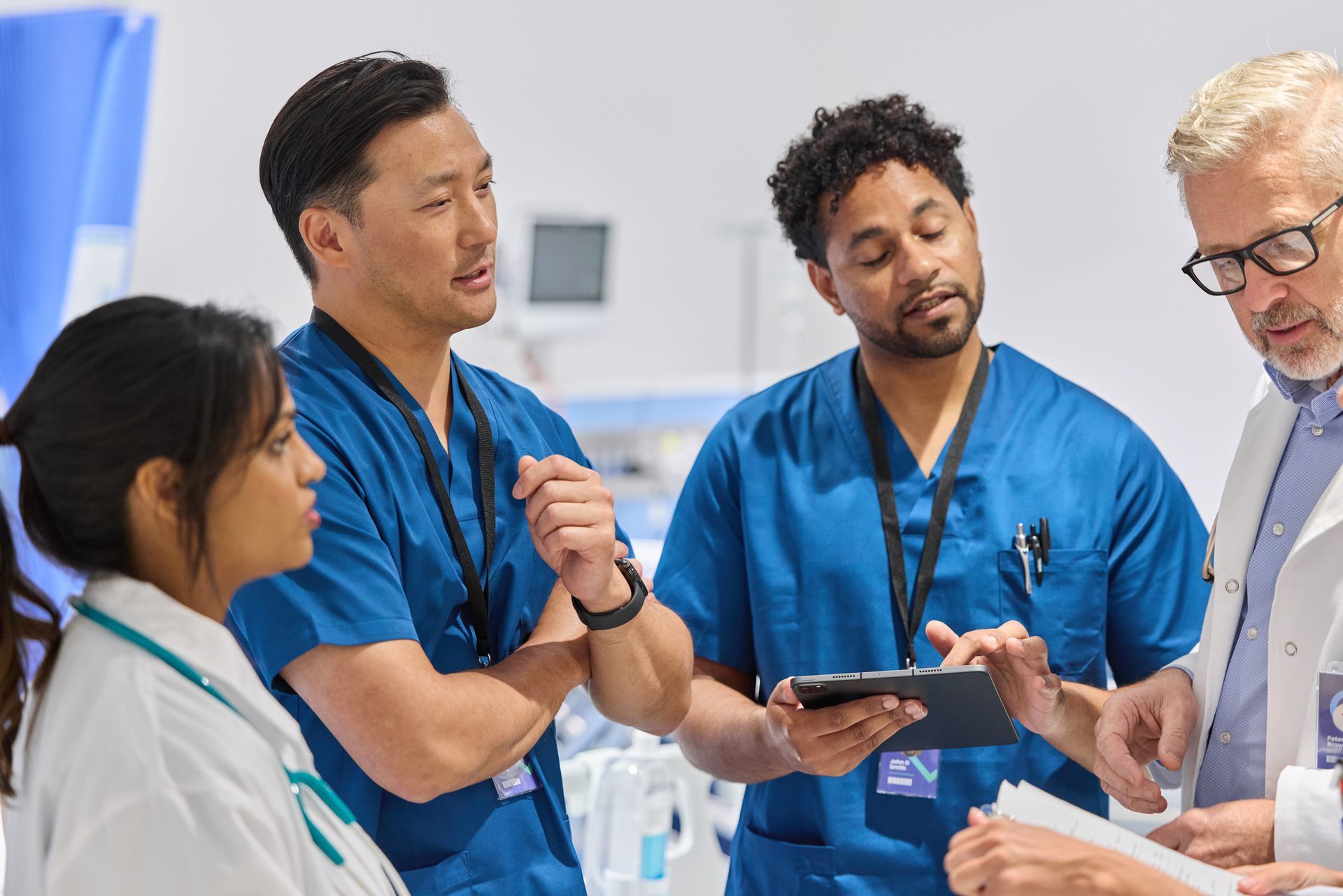 Male nurse and GP discussing patient care during a consultation in a clinic setting.