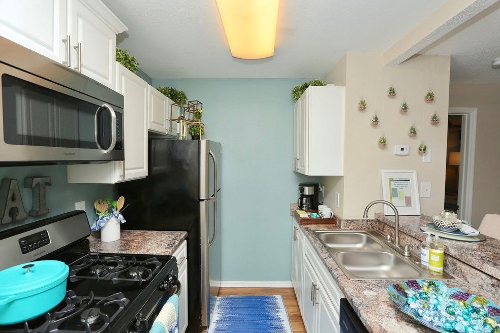 Bright modern kitchen with white cabinets, stainless appliances, granite countertops, and wood-look flooring