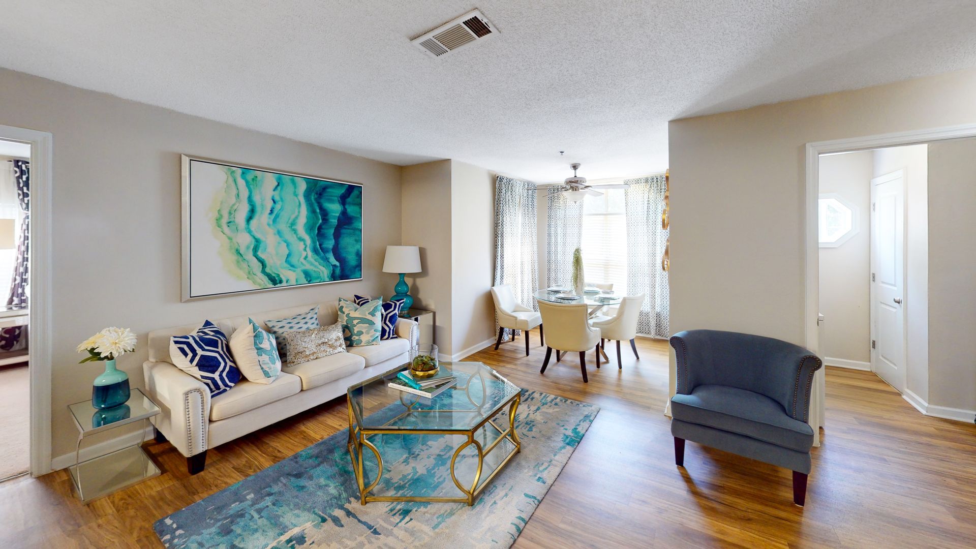Bright empty living room with white walls, wood floors, window, and stairs in the corner